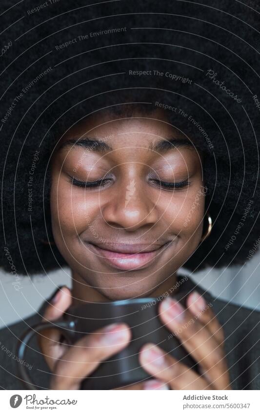 Positive schwarze Frau mit Heißgetränk Tasse Getränk Kaffee Afro-Look feminin Frisur verträumt Lächeln Vorschein Glück charmant brünett attraktiv heiter Inhalt