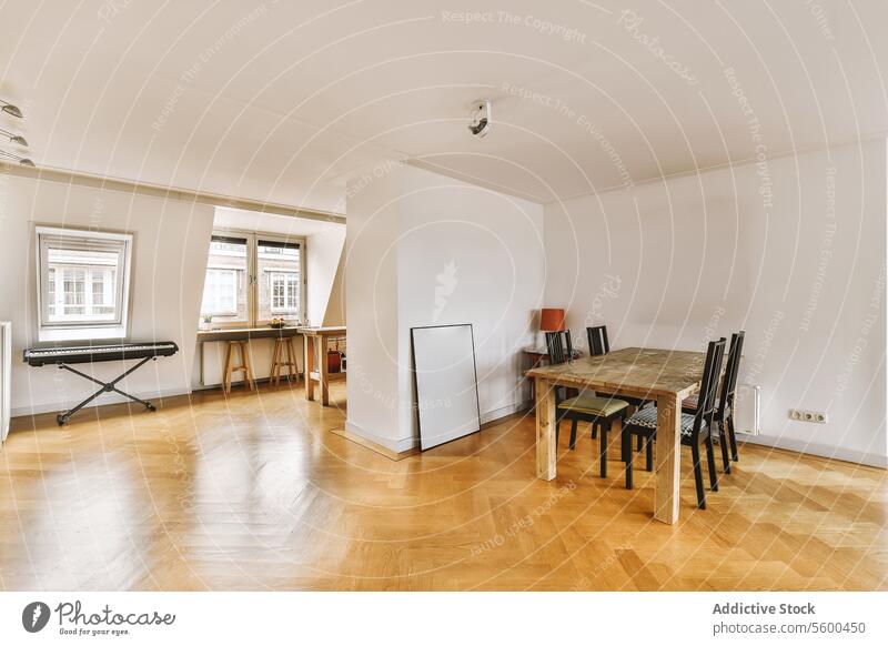 Speisesaal mit Holztisch und Stühlen Esszimmer speisend Tisch Stuhl geräumig Fenster Klavier weiß Wand Parkett Stock Möbel Tageslicht Musical Instrument Stil