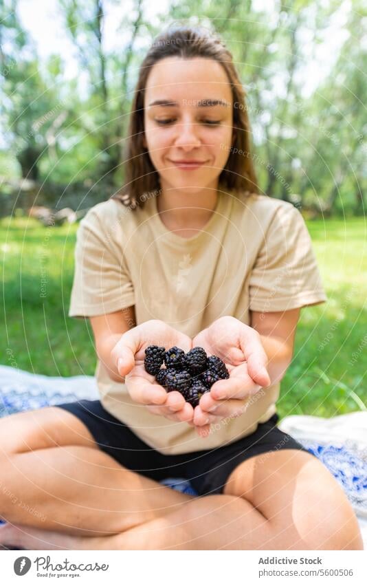 Frau genießt frische Brombeeren im Freien Frucht Lächeln Park Decke reif Beteiligung Sommer Picknick Garten Natur Gesundheit Snack lässig Freizeit Genuss sonnig