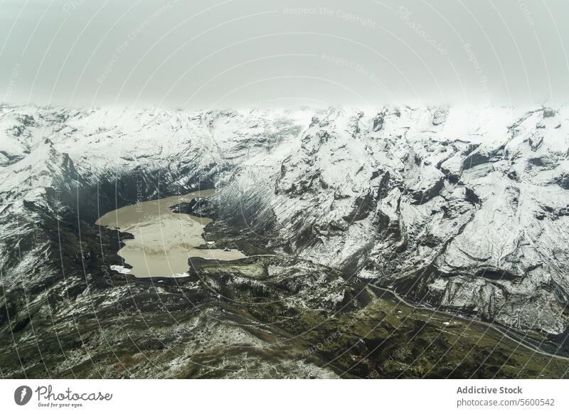 Schneebedeckte Berge mit See Berge u. Gebirge Antenne Ansicht robust Landschaft Decke halbgefroren wolkig Himmel Wildnis Natur weiß Winter Höhe Hochland