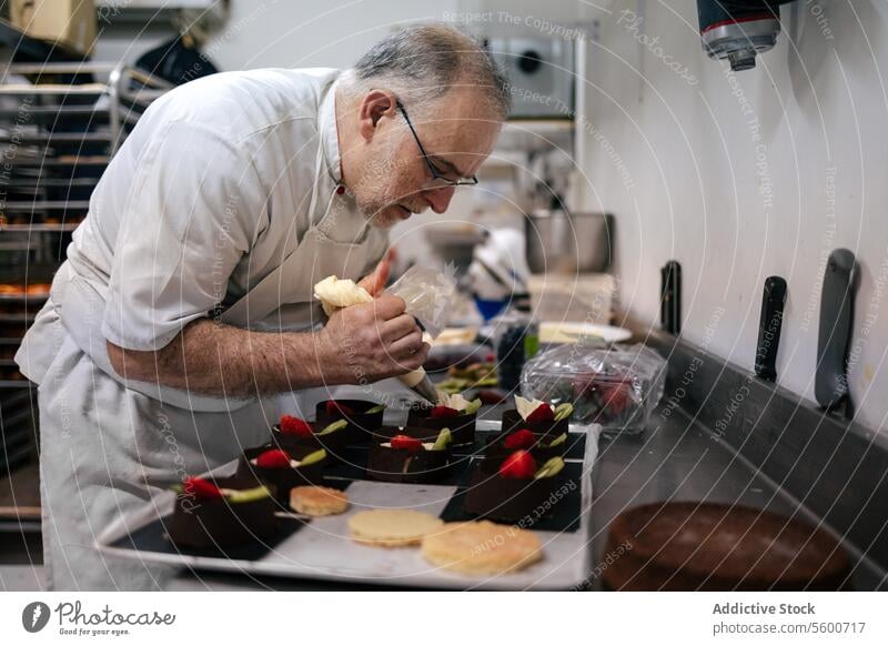 Konditorin mit einem Dressiersack Kuchen Küchenchef Mann Gebäck Tasche Sahne Dessert Dekoration & Verzierung süß Lebensmittel professionell geschmackvoll lecker