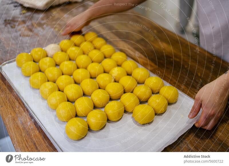 Porträt der gelben Teigkugeln Nahaufnahme Hände Heben Teigwaren Bälle Kurkuma Brot Bäckerei Tablett Lebensmittel Mehl Weizen frisch Hefe backen geschmackvoll