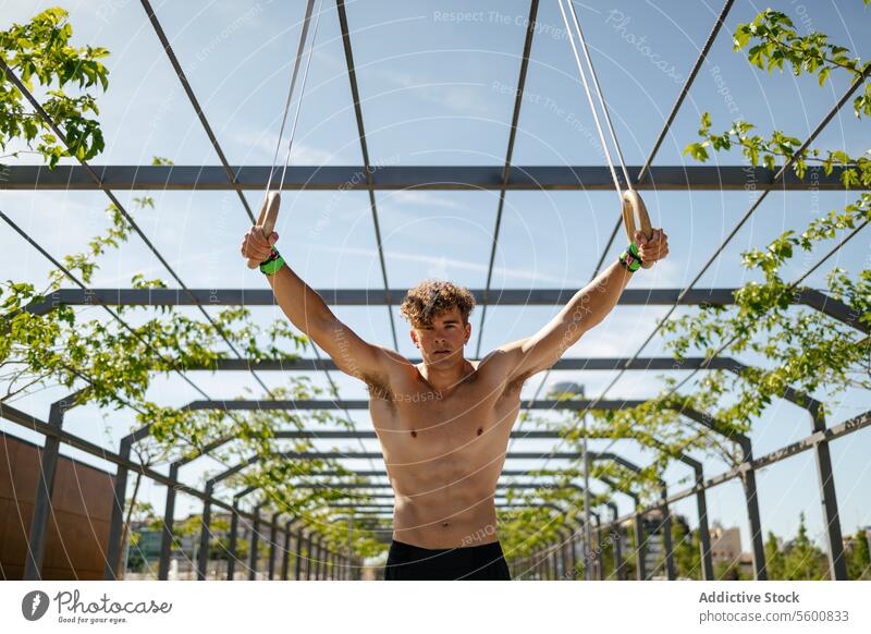 Starker junger Sportler beim Training mit Ringen Mann calisthenics Wellness Körpergewicht Übung Fitness Bodybuilding männlich Athlet Kunstturnen Person