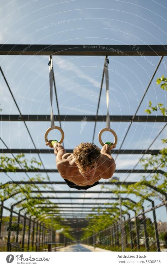 Starker junger Sportler beim Training mit Ringen Mann calisthenics Wellness Körpergewicht Übung Fitness Bodybuilding männlich Athlet Kunstturnen Person