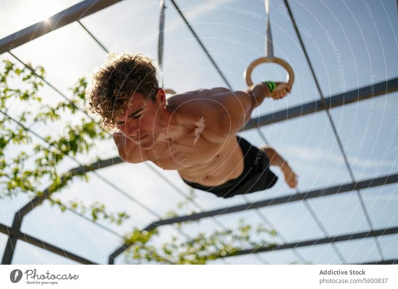 Starker junger Sportler beim Training mit Ringen Mann calisthenics Wellness Körpergewicht Übung Fitness Bodybuilding männlich Athlet Kunstturnen Person