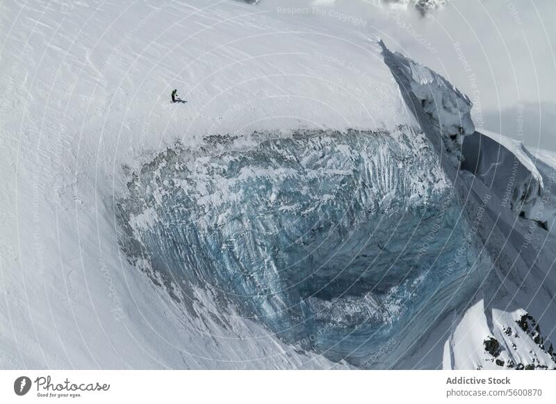 Von oben von anonymen Snowboarder Spaziergang vom Berg im Winter Tag in den Schweizer Alpen Schnee Landschaft verschneite Berghang Felsen Berge u. Gebirge