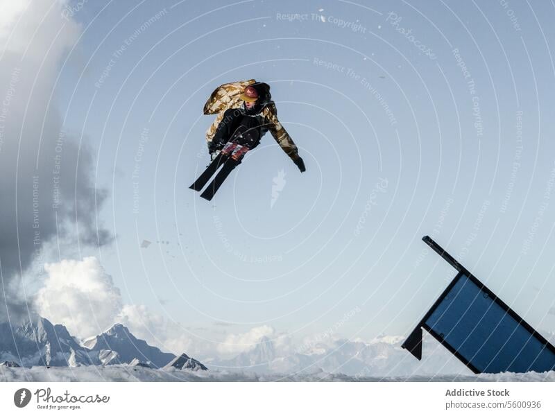 Anonymer Mann springt mit Snowboard auf Schweizer Alpen gegen blauen bewölkten Himmel anonym springen Snowboarder Schnee Berge u. Gebirge Blauer Himmel