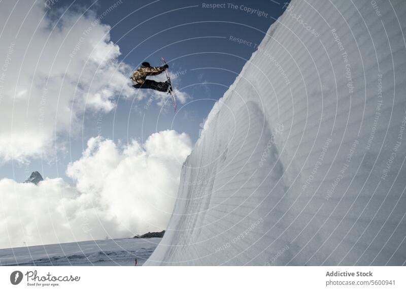 Anonymer Mann springt mit Snowboard auf Schweizer Alpen gegen blauen bewölkten Himmel anonym springen Snowboarder Schnee Berge u. Gebirge Blauer Himmel