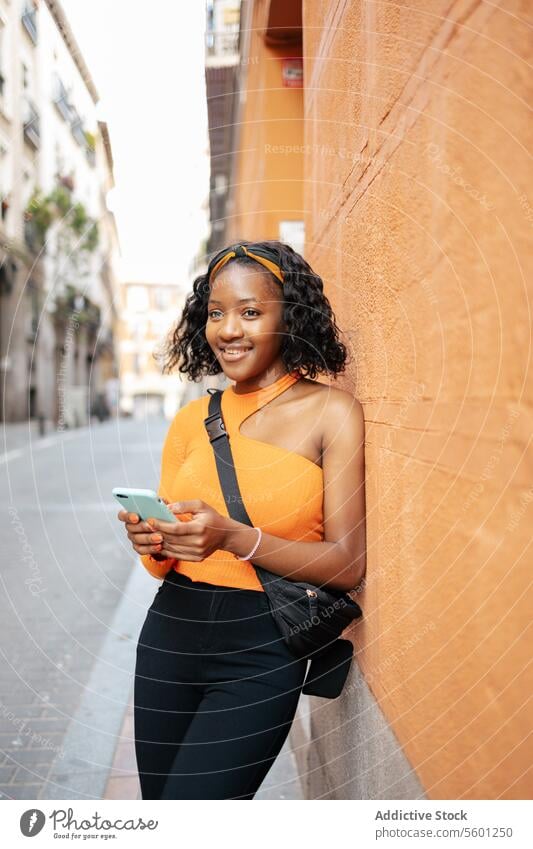 Porträt einer jungen schwarzen Frau, die ihr Smartphone auf der Straße benutzt Lifestyle Glück Technik & Technologie Texten Lächeln Mobile Person Telefon schön