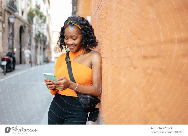 Porträt einer jungen schwarzen Frau, die ihr Smartphone auf der Straße benutzt Lifestyle Glück Technik & Technologie Texten Lächeln Mobile Person Telefon schön