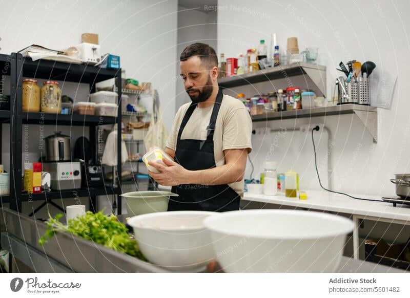 Junger Koch beim Kochen in einer professionellen Küche Küchenchef Essen zubereiten Lebensmittel Restaurant Gemüse Mann jung Arbeit männlich Speise Person Beruf