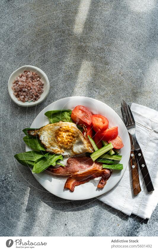 Von oben auf den gesunden Frühstücksteller mit Ei und Speck Teller Gesundheit Gemüse Tomate Salatgurke Spinat gebraten weiß Knusprig frisch Blätter