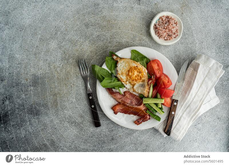 Von oben auf den gesunden Frühstücksteller mit Ei und Speck Teller Gesundheit Gemüse Tomate Salatgurke Spinat gebraten weiß Knusprig frisch Blätter