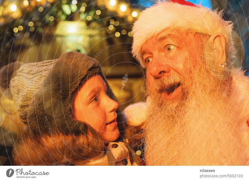 Kind in Ehrfurcht vor dem Weihnachtsmann auf einem Weihnachtsmarkt, umgeben von festlichen Lichtern Freude freudig Frohe Weihnachten Handschuhe traditionell