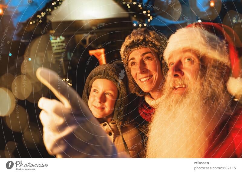 Familie mit Kind und Weihnachtsmann auf dem Weihnachtsmarkt, Bokeh-Lichter und Staunen in den Augen Tourist Tracht freudig Frohe Weihnachten traditionell