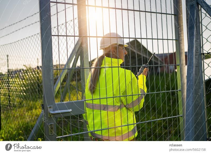 Technikerin mit Walkie-Talkie auf dem Weg zum Tor eines Solarfelds Technik & Technologie Pflanze Industrie Elektrizität Arbeiter Sicherheit Ingenieur ökologisch