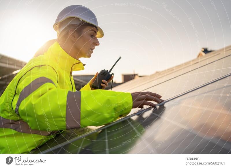 Solartechniker mit Walkie-Talkie bei der Inspektion von Solarmodulen in der Abenddämmerung. Alternative Energie ökologisches Konzept Bild. Meisteringenieur