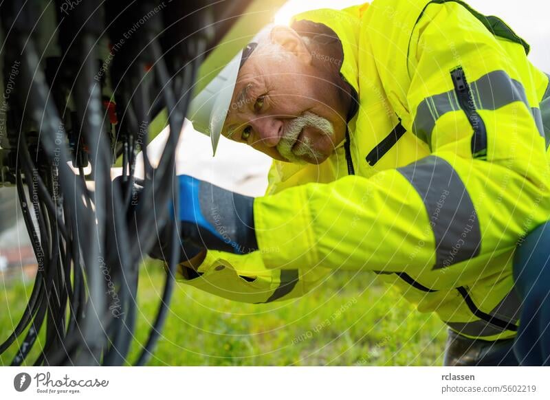 Älterer Arbeiter in Warnweste, der Kabel inspiziert. Alternative Energie ökologisches Konzept Bild. Ingenieur Solarpark Technik & Technologie Pflanze Industrie