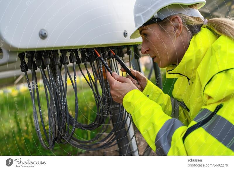 Techniker prüft Solarmodulkabel mit einem Multimeter in einem Solarpark. Alternative Energie ökologisches Konzept Bild. Technik & Technologie Pflanze Industrie