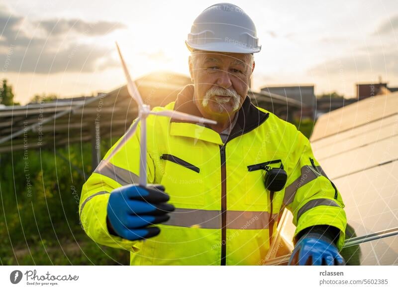 Ein leitender Ingenieur hält ein Windturbinenmodell in einer Solaranlage. Ökologisches Konzept für alternative Energie. Technik & Technologie Industrie