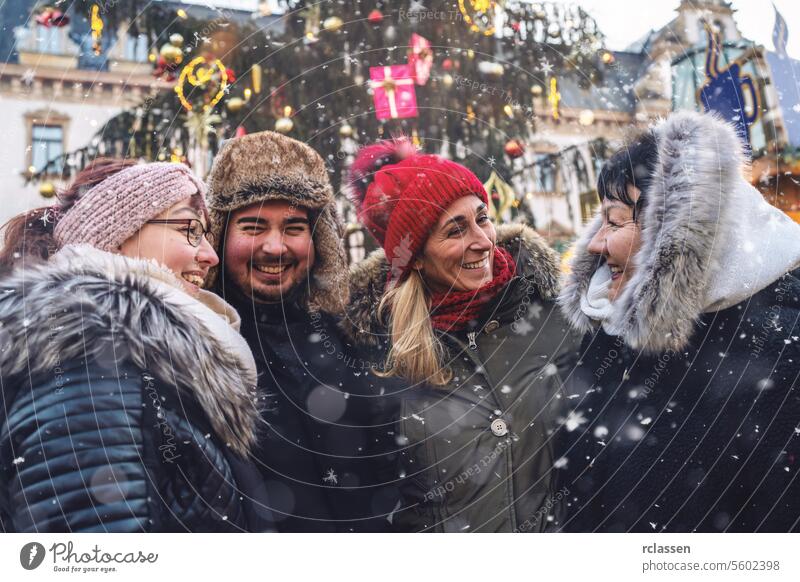 Fröhliche Gruppe von Freunden, die sich auf einem Weihnachtsmarkt treffen und gemeinsam lachen Sitzung Frohe Weihnachten Tasse Kakao Handschuhe traditionell