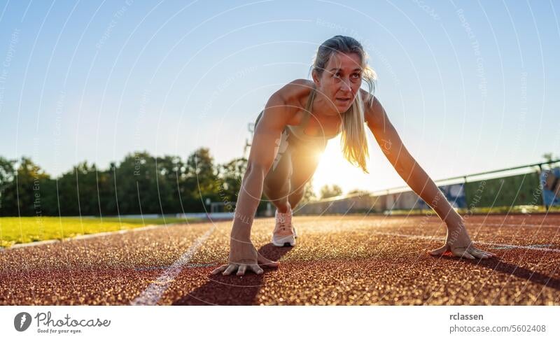 Entschlossene Sportlerin in Startposition auf der Laufbahn Ausgangsposition Tatkraft Sportbekleidung Fitness Bereitschaft Sprinter aktiver Lebensstil Konkurrenz