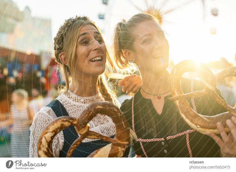 Zwei Freundinnen zusammen auf einer bayerischen Kirmes oder einem Oktoberfest oder in Tracht oder Dirndl mit Brezn oder Brezen Frau Party brezen Brezel