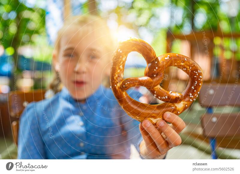 Junges Mädchen mit traditioneller bayerischer Brezel in Tracht, Dirndl, im Biergarten oder auf dem Oktoberfest in Bayern, Deutschland Hand brezen Familie