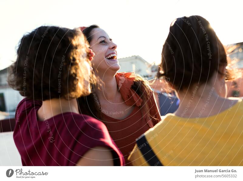 Eine Gruppe von Freunden, die unter dem warmen Licht des Sonnenuntergangs herzhaft lachen und die Gesellschaft und das Glück des gemeinsamen Moments genießen