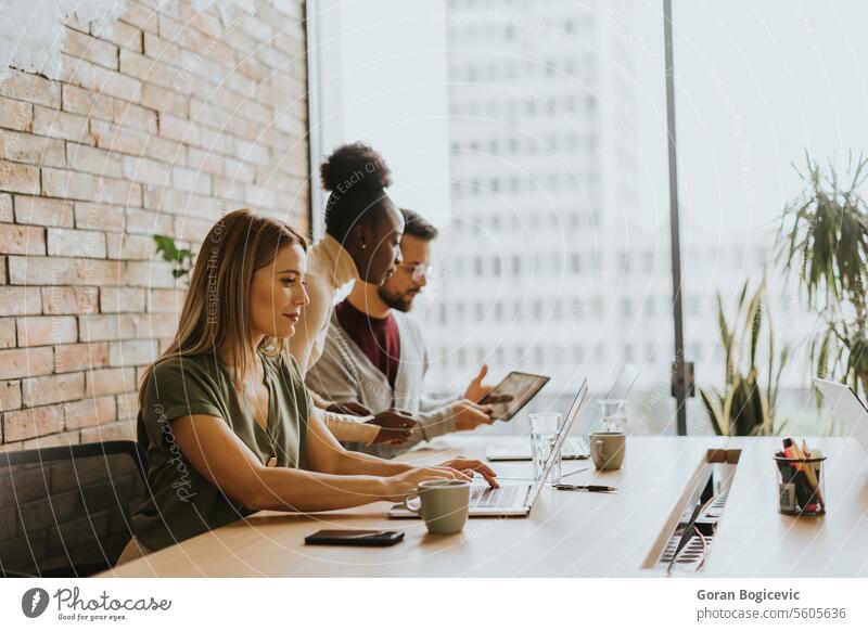 Junges multiethnisches Startup-Team bei der Arbeit an der Backsteinmauer in einem Büro im Industriestil schwarz Afrikanisch Amerikaner jung Glück Laptop