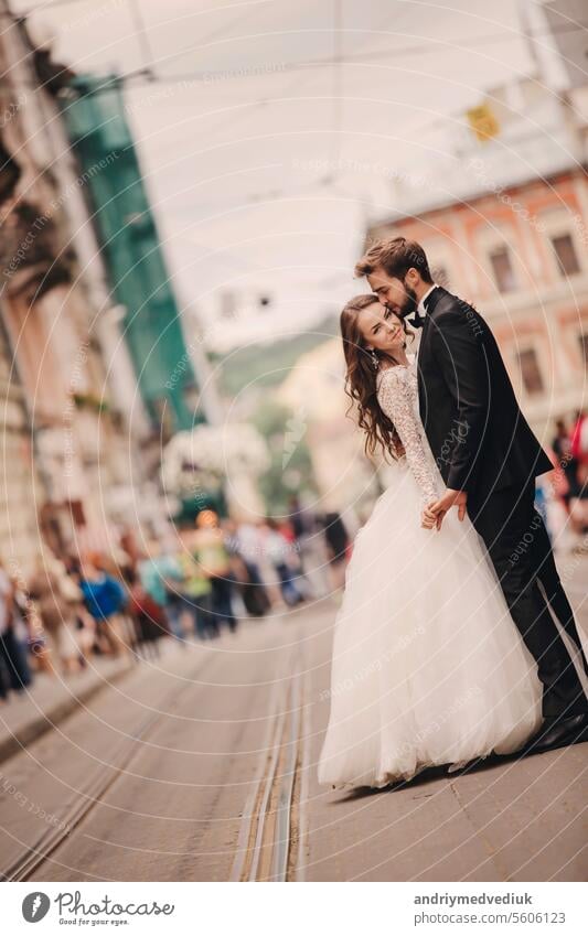 Happy newlyweds Paar auf einem Spaziergang in alten europäischen Stadt Straße, wunderschöne Braut in weißem Hochzeitskleid zusammen mit gut aussehenden Bräutigam.