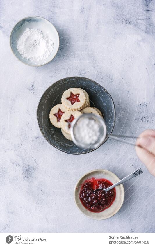 Eine Frau streut Puderzucker über Mürbteigkekse. Draufsicht. Weihnachten & Advent Kekse Dessert Weihnachtsgebäck backen Plätzchen lecker süß Vorweihnachtszeit