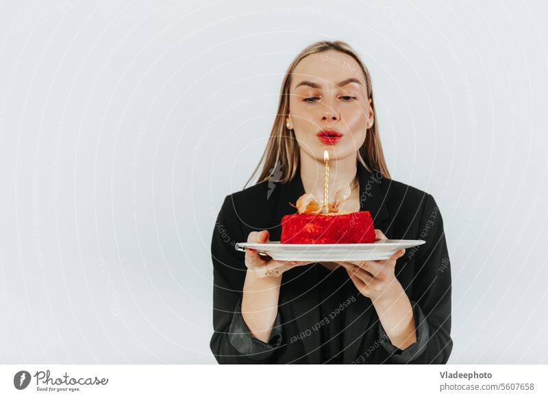 Ausblasen der Geburtstagskerzen. Attraktive junge Frau, die sich etwas wünscht, während sie einen roten Kuchen hält Wunsch Kerze Schlag feiern attraktiv allein