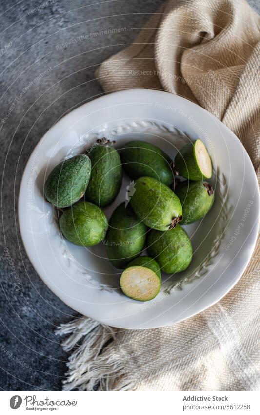 Frische Feijoa-Früchte auf einem Keramikteller feijoa Frucht frisch roh Teller grün halbgeschnitten Zellstoff rustikal texturiert Hintergrund Lebensmittel