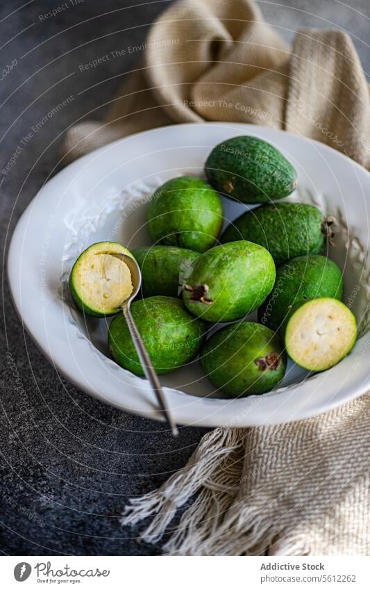 Frische Feijoa-Früchte in einer weißen Schale vor einem rustikalen Hintergrund feijoa Frucht Schalen & Schüsseln Keramik reif frisch geschnitten offen