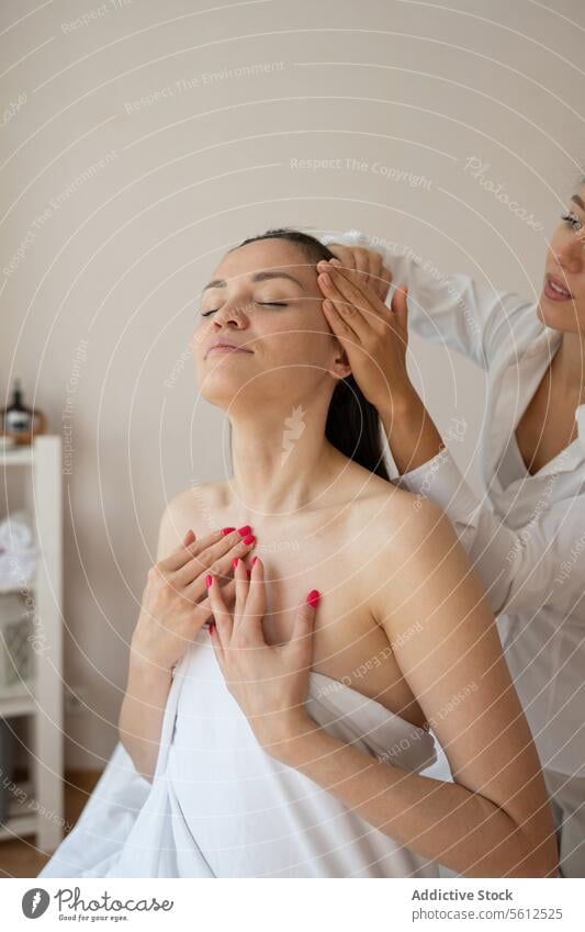 Crop-Hände einer nicht erkennbaren Masseurin bei der Haarmassage einer barbusigen Kundin, die die Therapie mit geschlossenen Augen in einem Spa genießt Kunde