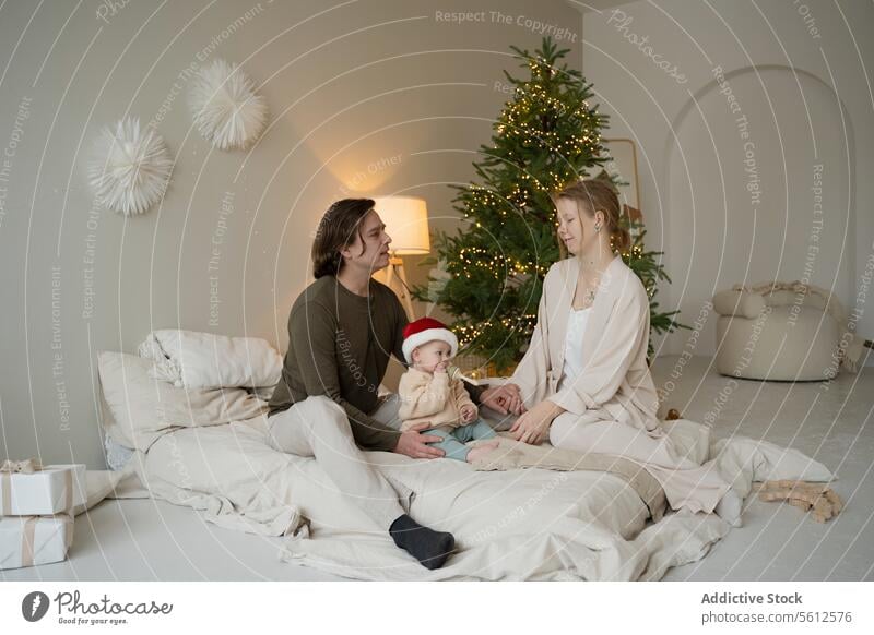 Die Familie genießt einen gemütlichen Weihnachtsmorgen zusammen Weihnachten Morgen heimwärts Baby Weihnachtsmütze Geschenke Baum speziell Moment jung Eltern