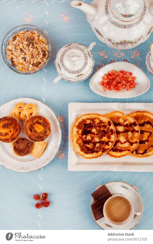 Elegantes Layout für die Teezeit mit Snacks und Teeservice elegant Zeit von oben nach unten Ansicht Aufstrich Teekanne Tasse Hintergrund blau Waffel Torte Müsli