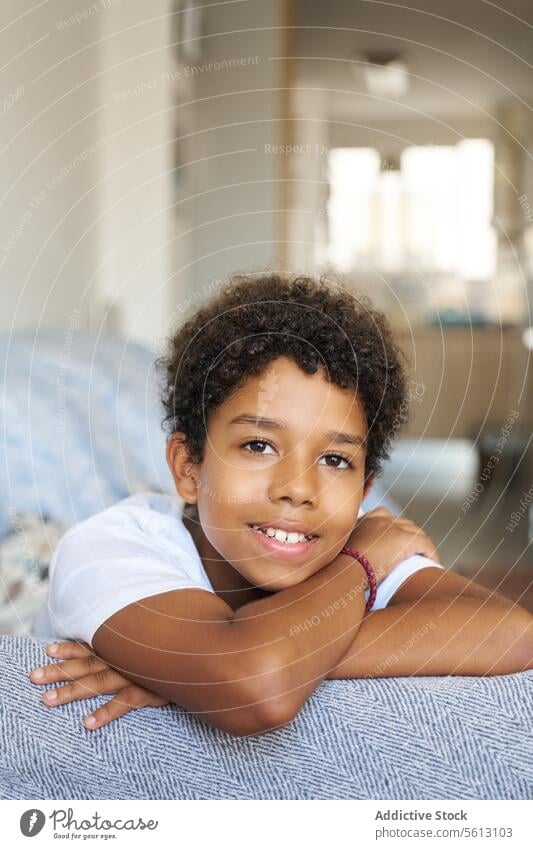 Glücklicher Junge ruht sich zu Hause auf der Couch aus Porträt Lächeln Nahaufnahme Sofa Lehnen Wohnzimmer heimwärts Blick schwarz bequem Windstille