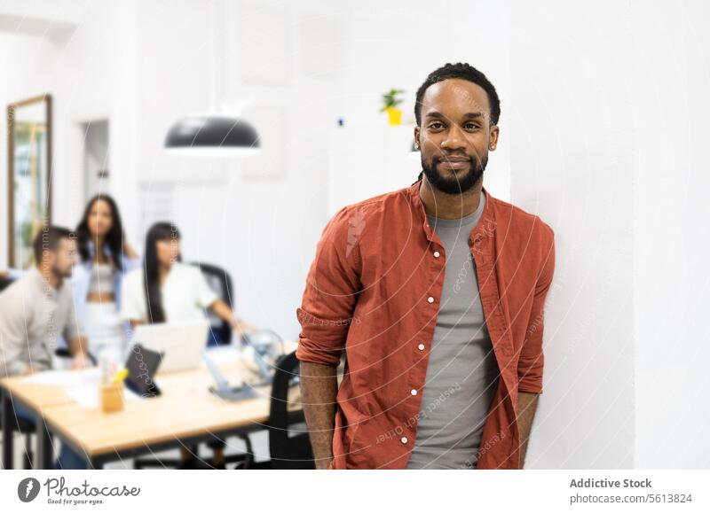 Selbstbewusster Geschäftsmann in Freizeitkleidung im Coworking-Büro Selbstvertrauen kreativ Porträt Lächeln Arbeitsplatz Stehen Wand jung Hemd professionell