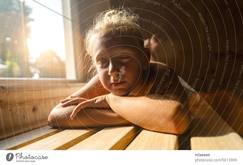 Kind auf einer Saunabank ruhend, Sonnenlicht fällt durch ein Fenster, Augen geschlossen Hotel Bademantel Schönheitssalon Windstille bequem genießen Schweiß heiß