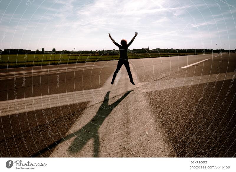 Sprung auf der Landebahn springen Frau Startbahn Himmel Wolken Flugplatz Schattenspiel Horizont Sonnenlicht Bodenmarkierung Asphalt Ferne Lebensfreude Freiheit