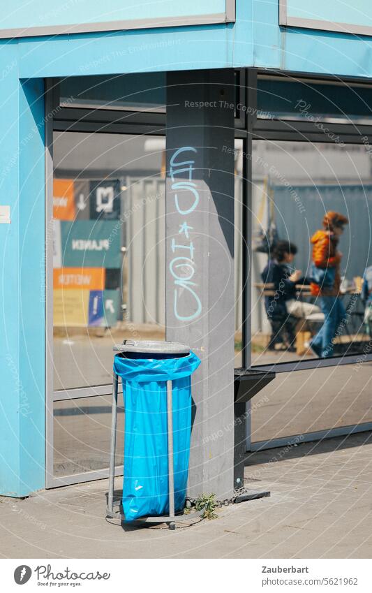 Ecke eines Hauses in hellblau, Mülltüte in blau, Glasfassade und gespiegelte Person, urbane Straßenszene Mülltütenhalter Spiegelung street Leben Stadtleben