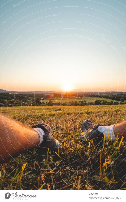 Die Füße eines Wanderers werden vom orange-roten Licht der Sonne gegen den dunklen Himmel beleuchtet. Beskiden, Tschechische Republik Freiheit Sonnenuntergang