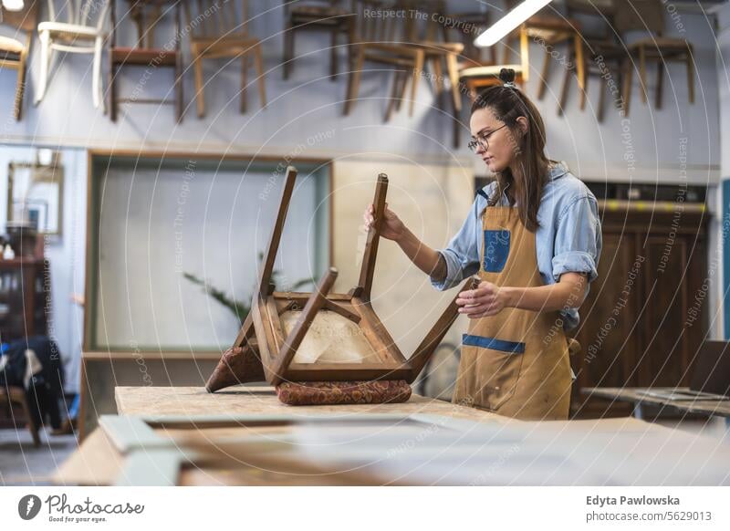 Schreinerin bei der Arbeit in ihrer Werkstatt Möbel Zimmerer wiederherstellend Schreinerei Holz Stuhl Gebäude Herstellung Handwerk Renovierung reparierend