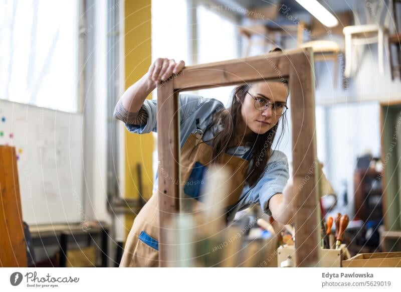 Schreinerin bei der Arbeit in ihrer Werkstatt Möbel Zimmerer wiederherstellend Schreinerei Holz Stuhl Gebäude Herstellung Handwerk Renovierung reparierend