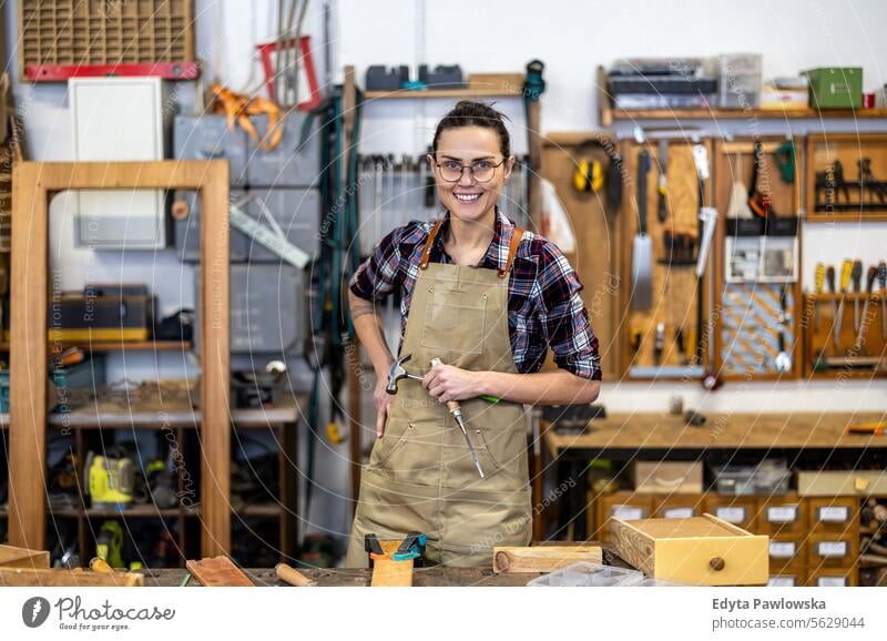 Porträt einer selbstbewussten Schreinerin in ihrer Werkstatt Möbel Zimmerer wiederherstellend Schreinerei Holz Stuhl Gebäude Herstellung Handwerk Renovierung