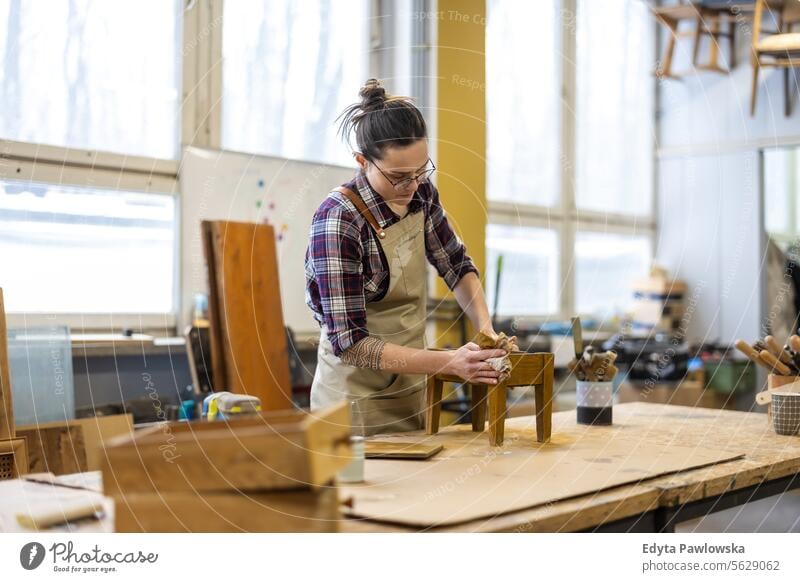 Porträt einer jungen Schreinerin bei der Arbeit in ihrer Werkstatt Möbel Zimmerer wiederherstellend Schreinerei Holz Stuhl Gebäude Herstellung Handwerk