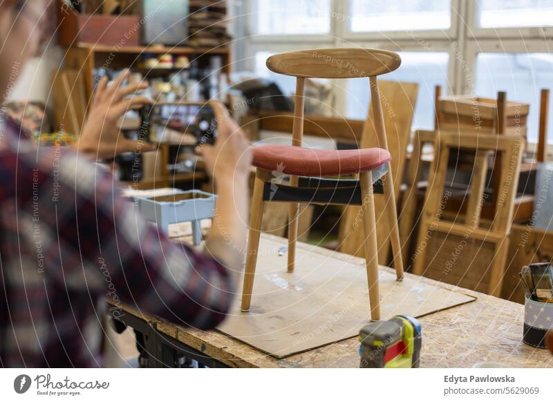 Handwerkerin beim Fotografieren eines renovierten Stuhls Möbel Zimmerer wiederherstellend Schreinerei Holz Gebäude Herstellung Renovierung reparierend Nutzholz