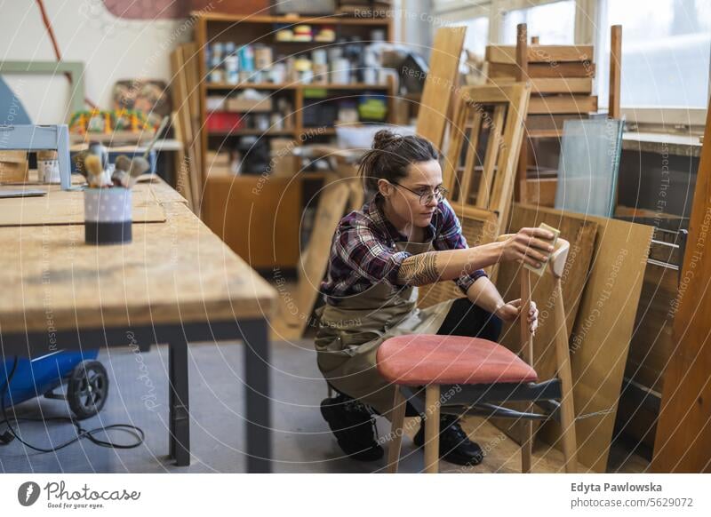 Schreinerin bei der Arbeit in ihrer Werkstatt Möbel Zimmerer wiederherstellend Schreinerei Holz Stuhl Gebäude Herstellung Handwerk Renovierung reparierend